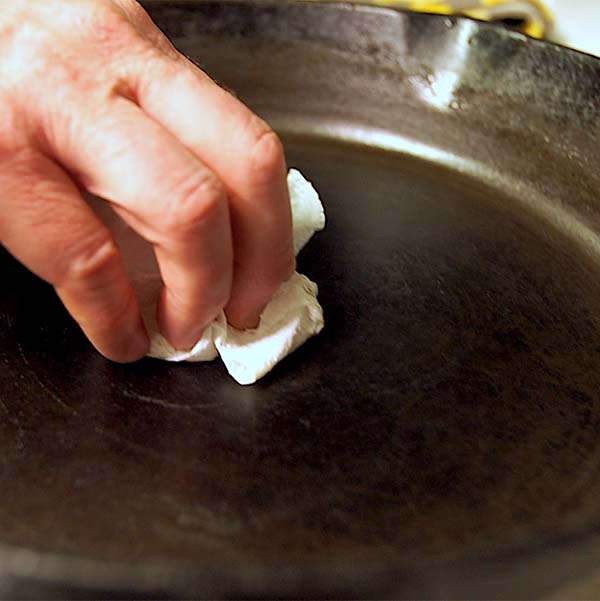 Next step to clean, care for cast iron is, dump out the water and dry your cast iron Dutch oven or skillet with a paper towel.