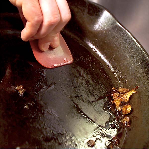 The first step to clean, care for cast iron is scraping out all the visible food residue.